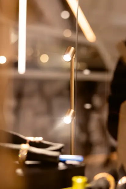 LED Vitrinenbeleuchtung als aufgeständerte Aufbauleuchte in Glasvitrine – gezielte, blendfreie Ausleuchtung zur Fokussierung auf hochwertige Produkte im POS und Ladenbau