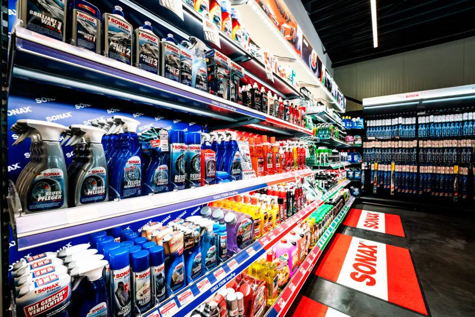 Beleuchtetes SONAX Produktregal im Automotive-Bereich mit klar strukturierter Warenpräsentation.